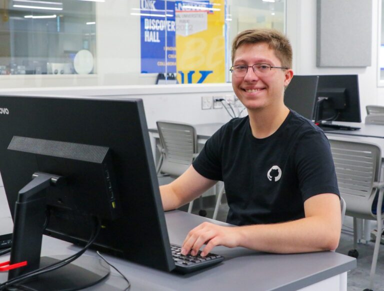 Trey Svatos poses in front of a computer